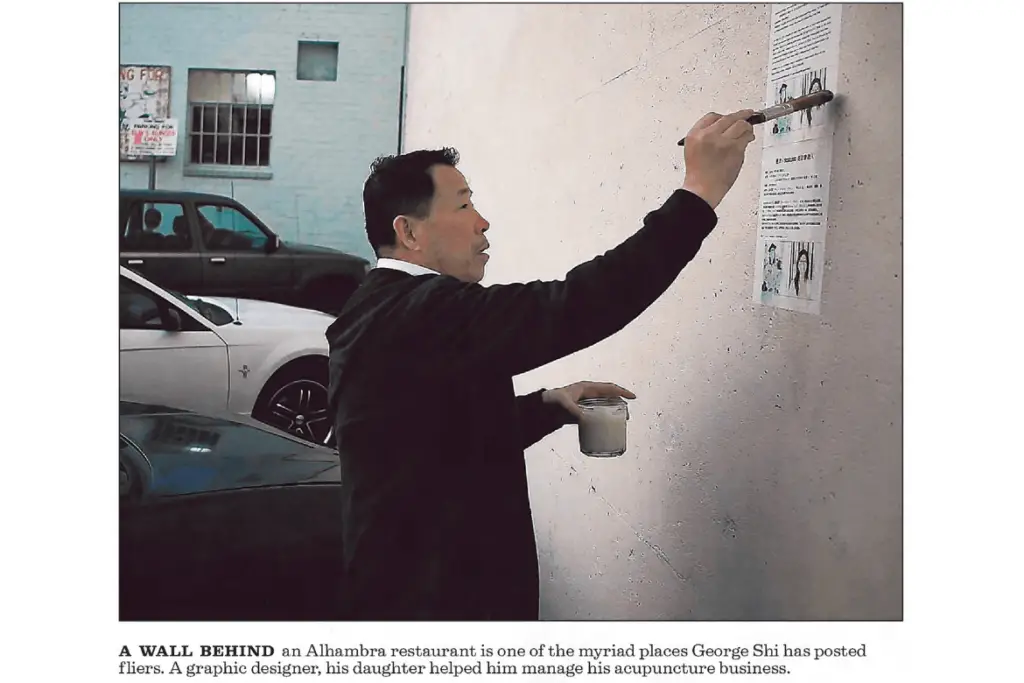 George Shi posting fliers on the wall of an Alhambra restaurant.